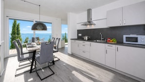 Una cocina moderna con armarios blancos, un microondas y un comedor con mesa y sillas.
