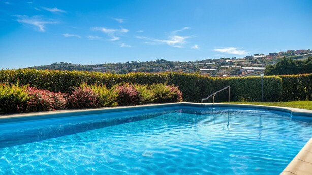 Una piscina azul cristalina con vistas a un pueblo en la colina.
