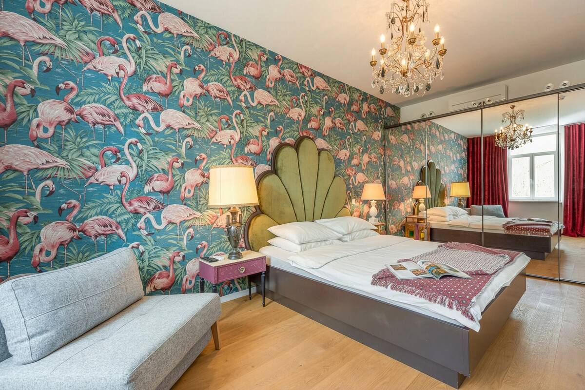 Quarto com uma cama grande, mesa de cabeceira, cômoda, espelho e lustre.