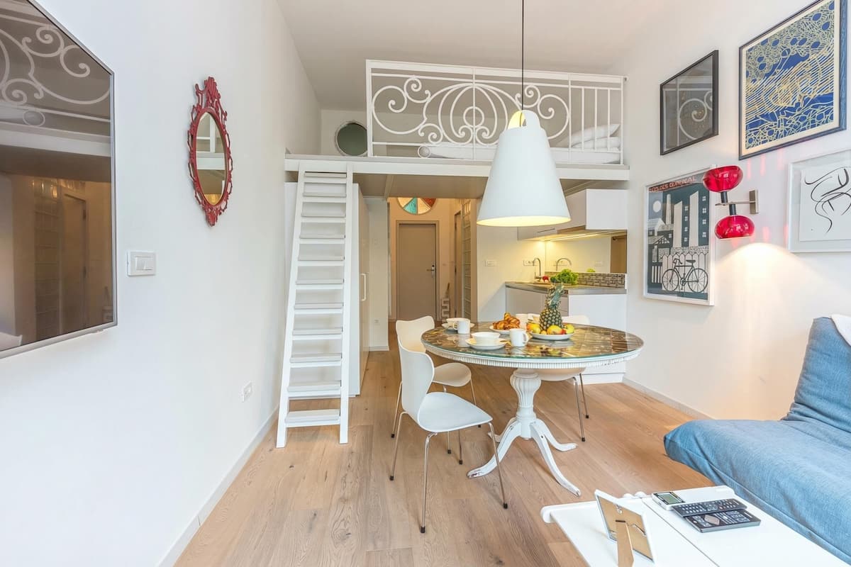 Uma área de refeições com uma mesa redonda, cadeiras brancas, uma luminária pendente branca e um design de teto branco.