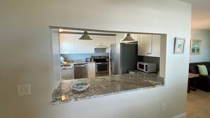 A modern kitchen with white cabinets, stainless steel appliances, and a granite countertop. - Gulf Front Vacation Rental- Anna Maria Island, Florida (Anna Maria)
