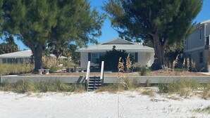 A house with a covered porch, surrounded by sand and sparse vegetation. - Gulf Front Vacation Rental- Anna Maria Island, Florida (Anna Maria)
