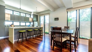 Une cuisine moderne dotée d’un îlot central, de tabourets de bar et d’un coin repas avec des chaises en bois.