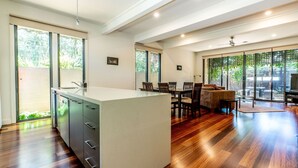 Une cuisine moderne dotée d’un grand îlot central, de planchers en bois et de grandes fenêtres qui laissent entrer la lumière naturelle.