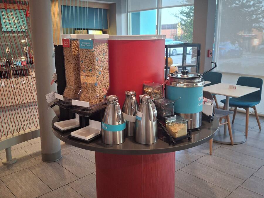 Ein Buffetbereich mit verschiedenen Speisebehältern, einer Kaffeestation und Sitzmöglichkeiten.