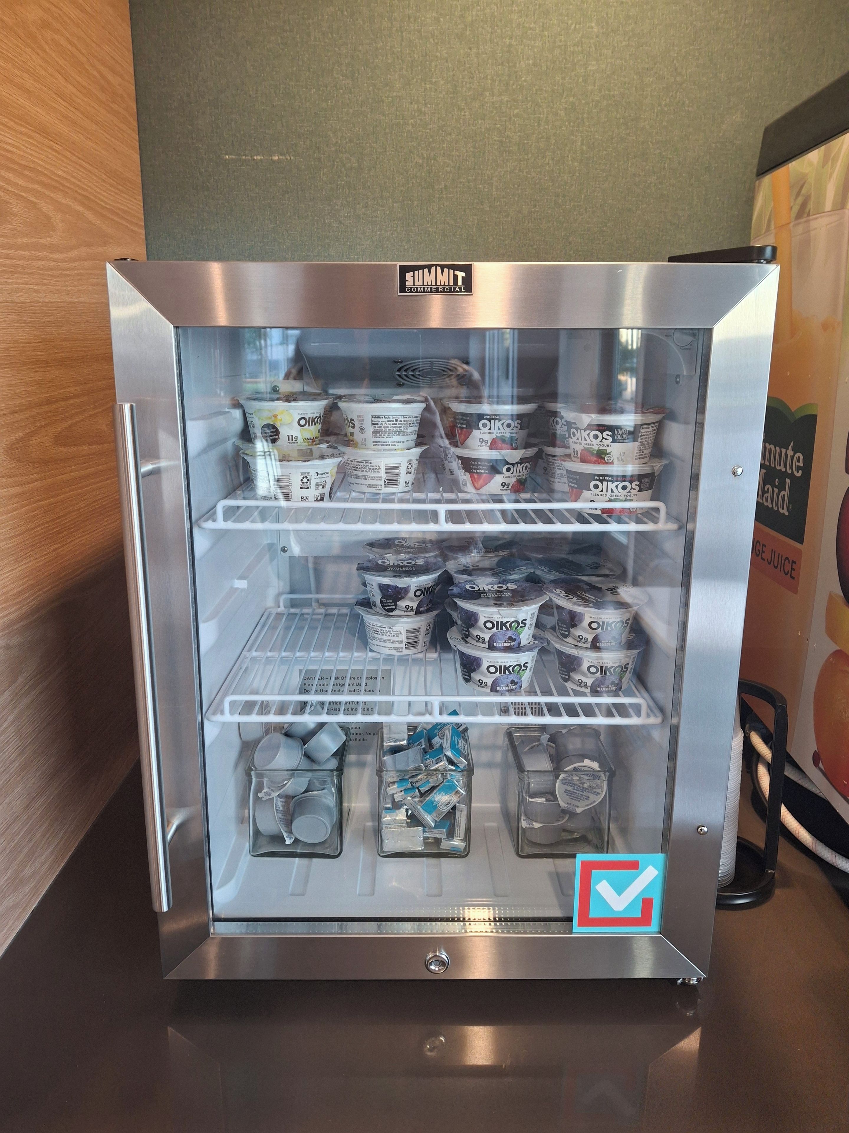 Un refrigerador comercial repleto de diversos productos lácteos, entre ellos yogures y leche.