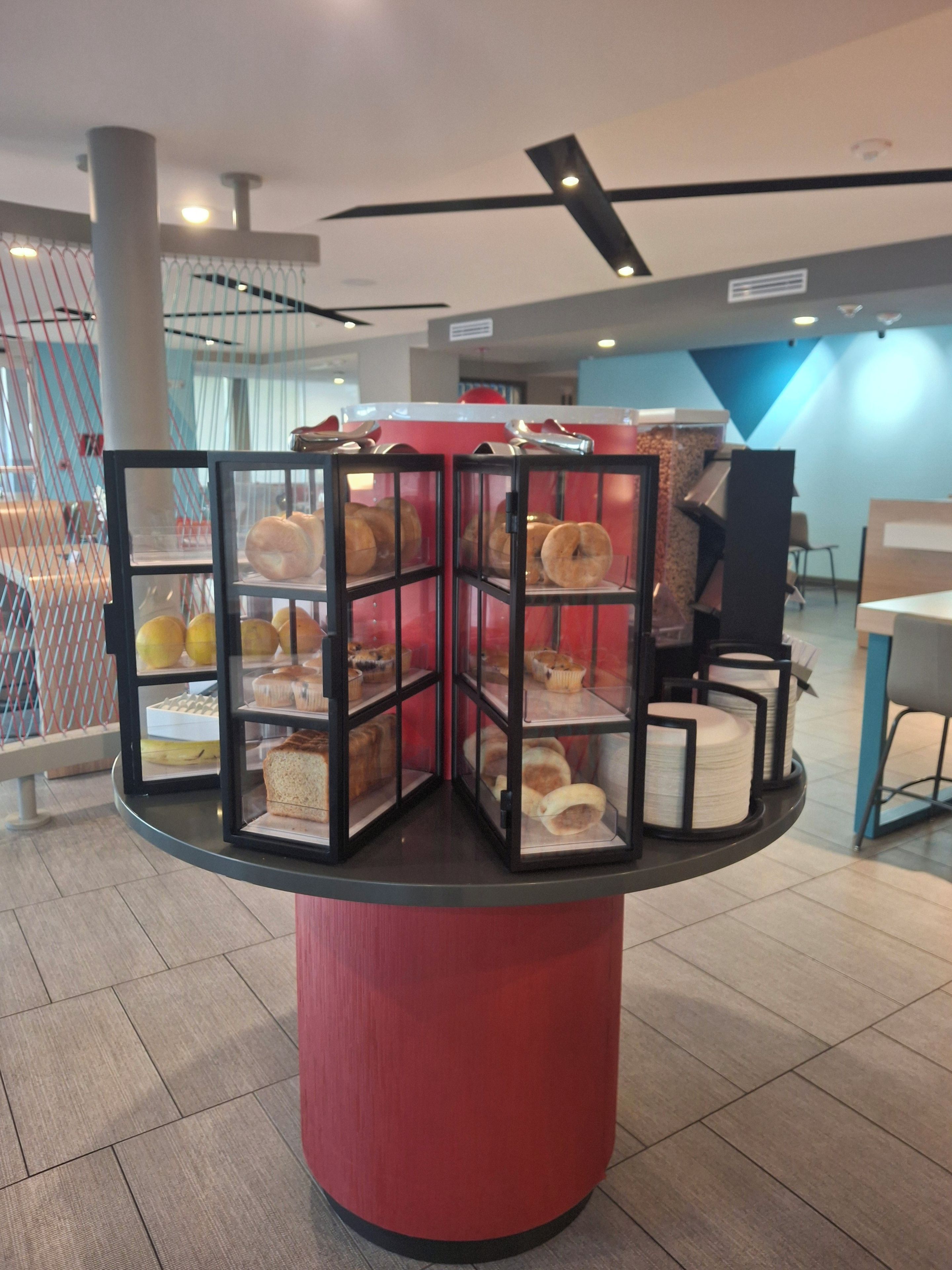 Un expositor circular con varias estanterías de vidrio que exhiben diversos productos de repostería.