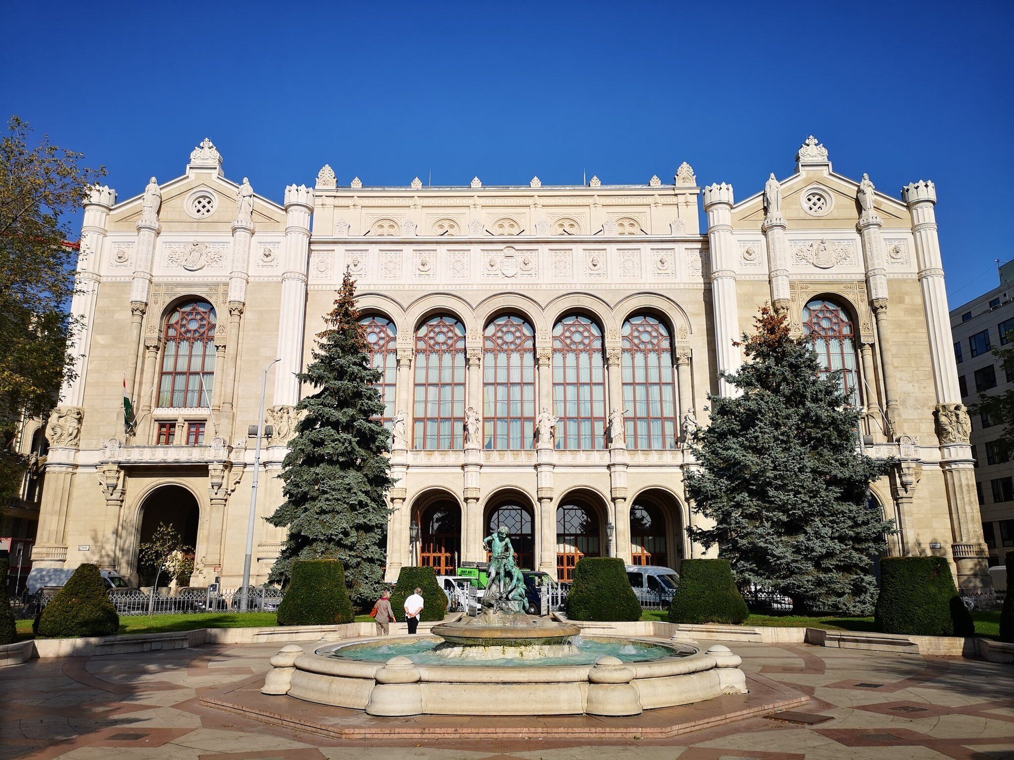 A grand building with a central fountain, symmetrical architecture, and statues.