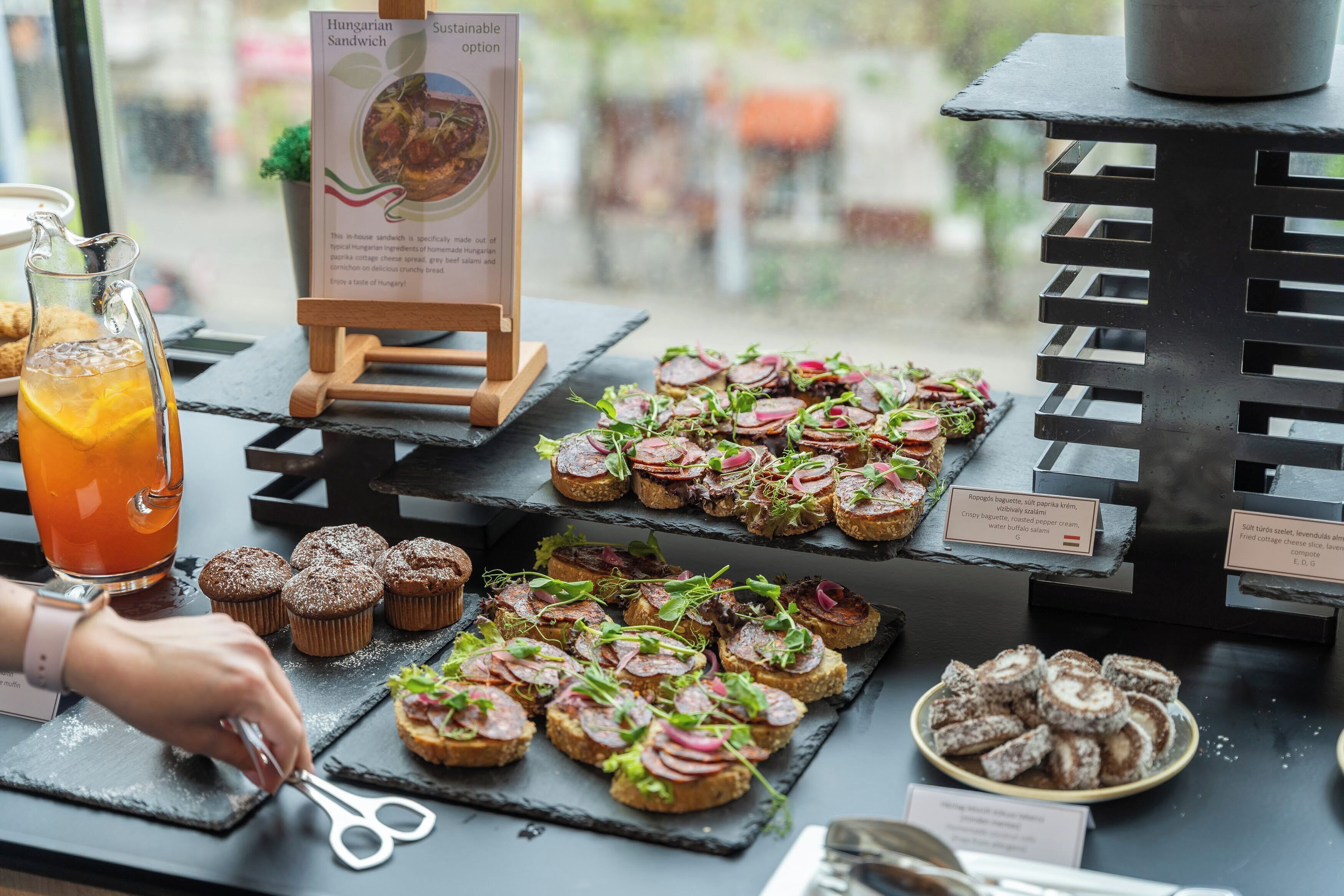 Un tavolo per buffet con diversi cibi, un cartello segnaletico e un bricco per bevande.