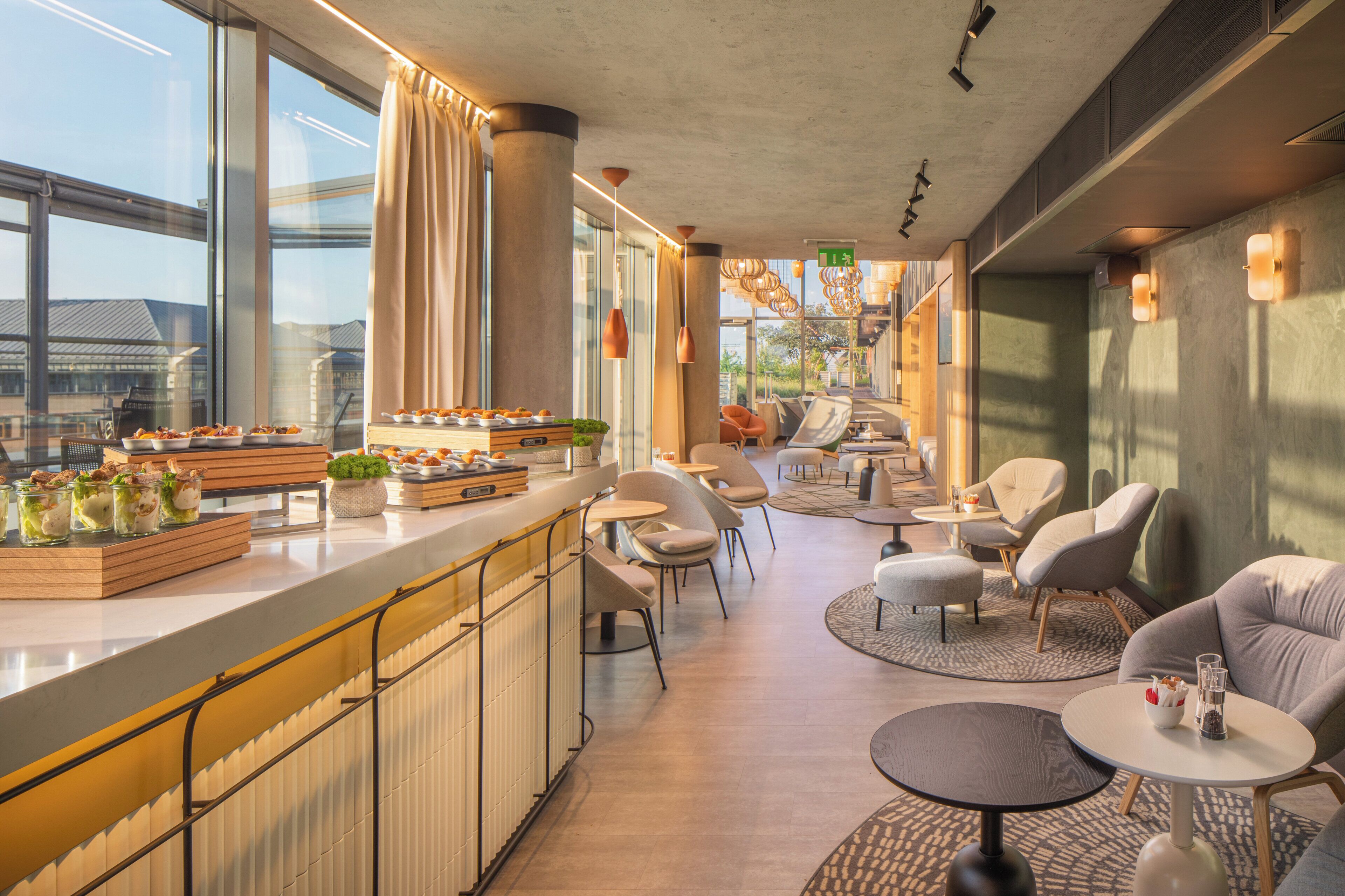Un interior moderno con zona de bar, asientos y grandes ventanales.