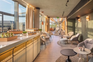 A modern interior with a bar area, seating, and large windows. - Crowne Plaza Budapest by IHG (Budapest)