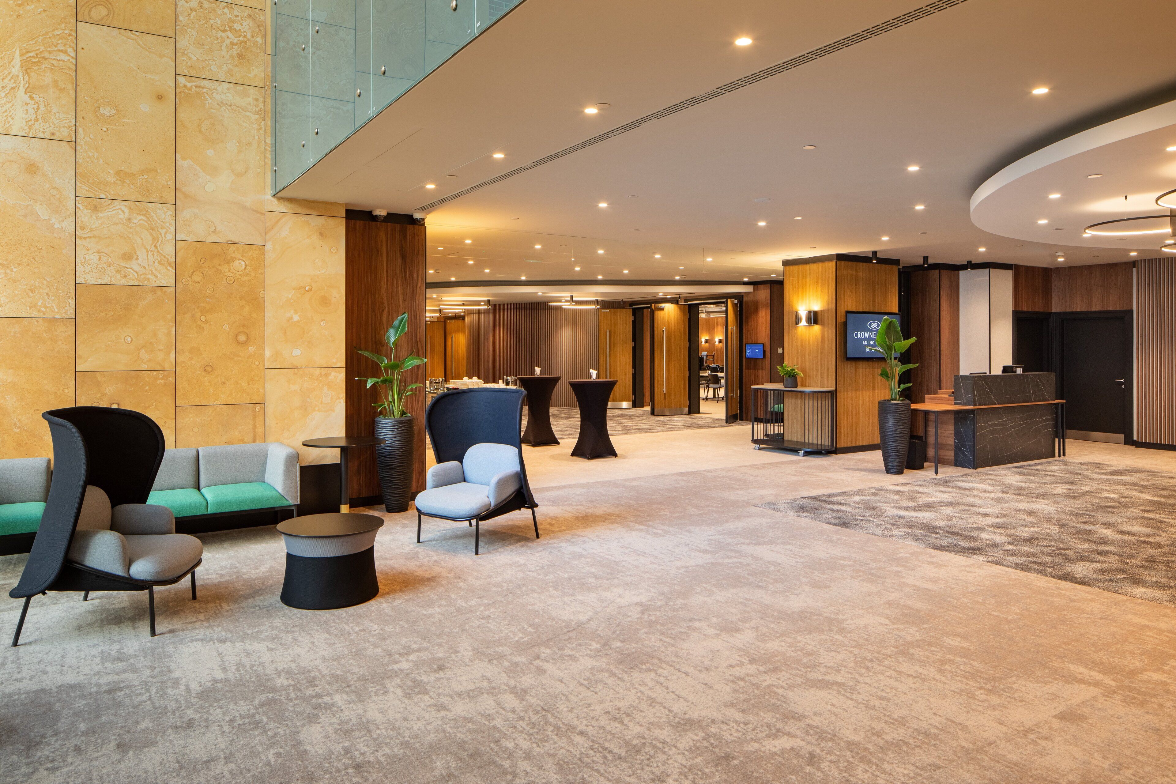 Um lobby de hotel moderno com balcão de recepção, área de estar e uma grande planta.
