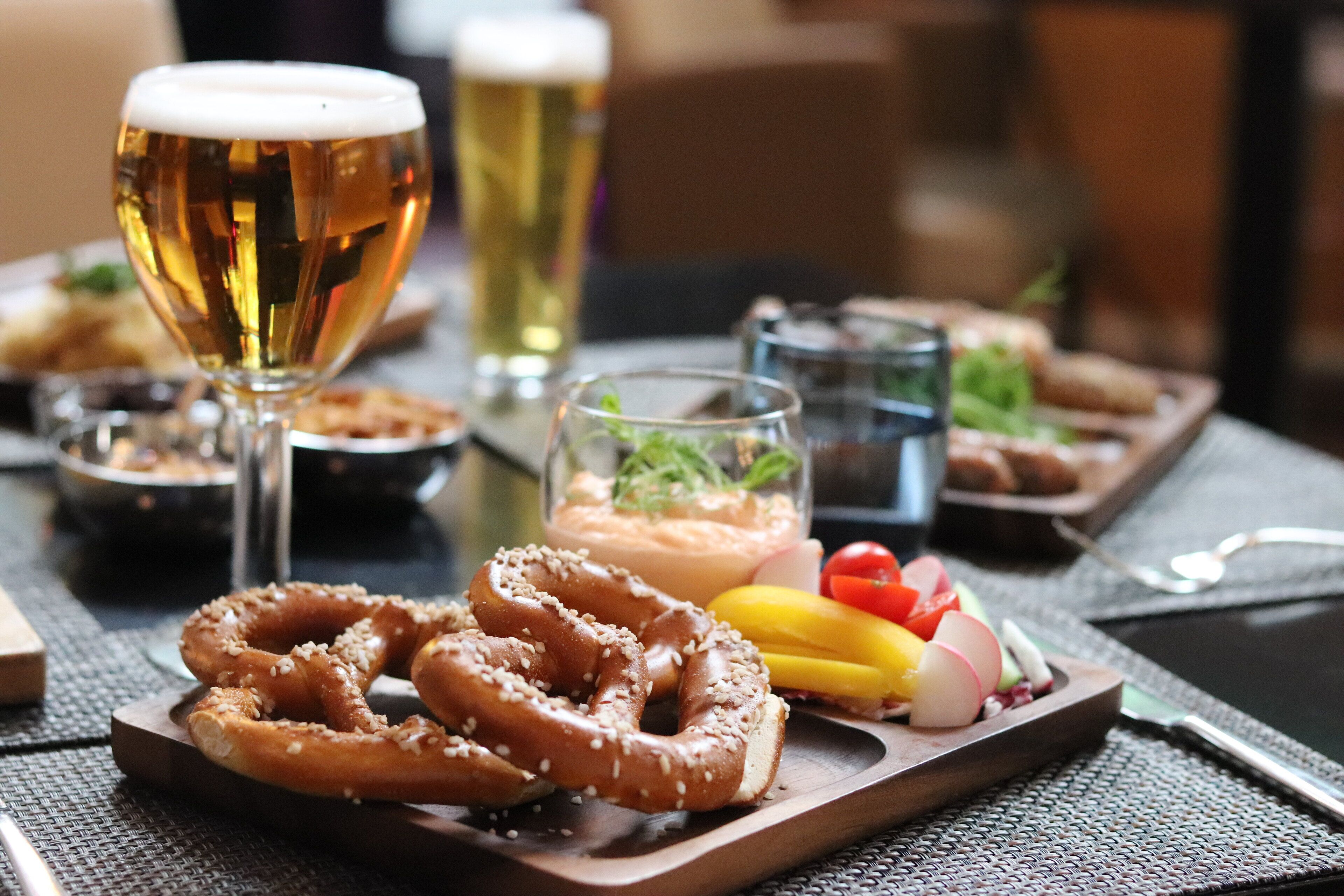 Una mesa con pretzels, una jarra de cerveza y diversos bocadillos.