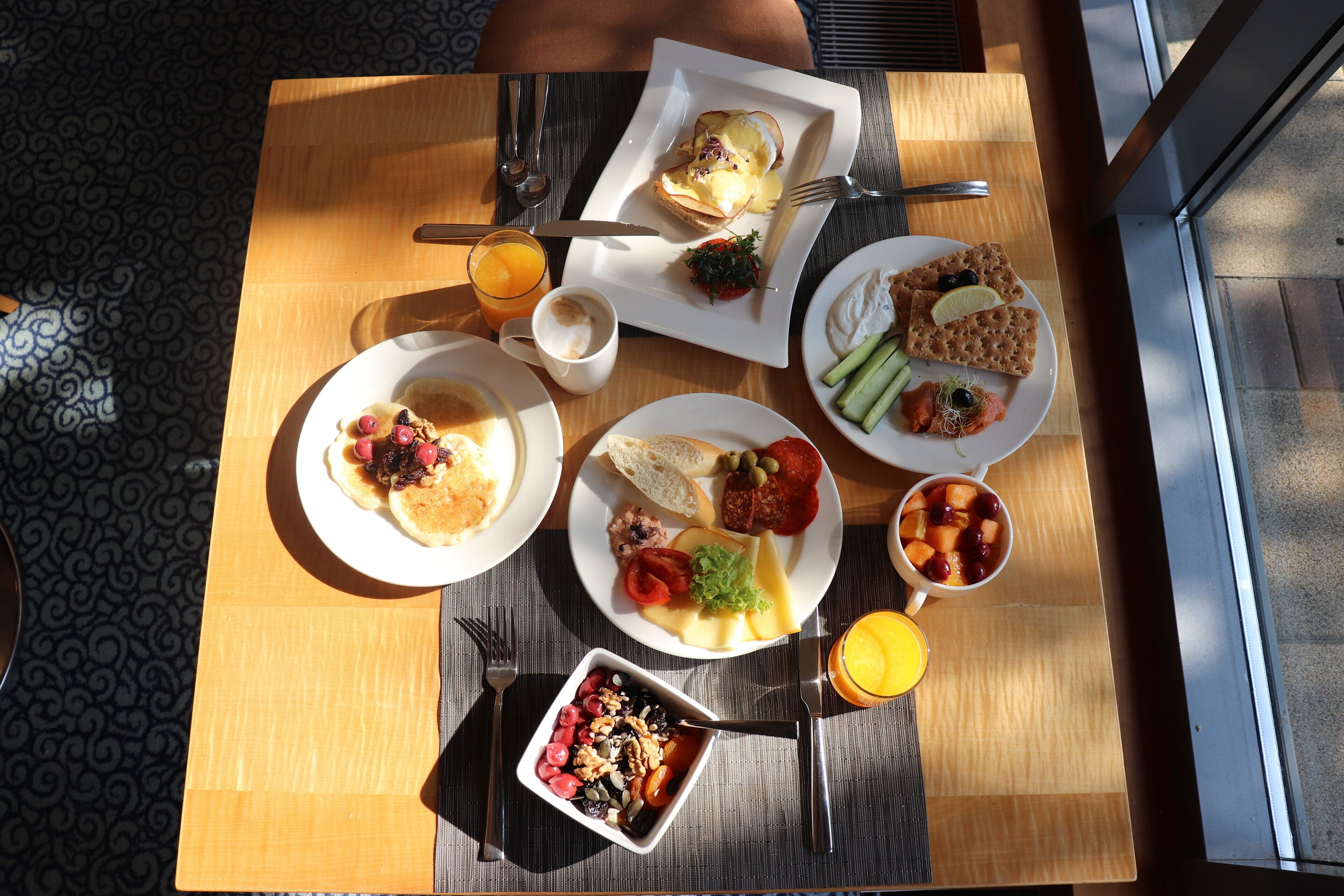A table with breakfast items including pancakes, eggs, toast, and fruit.