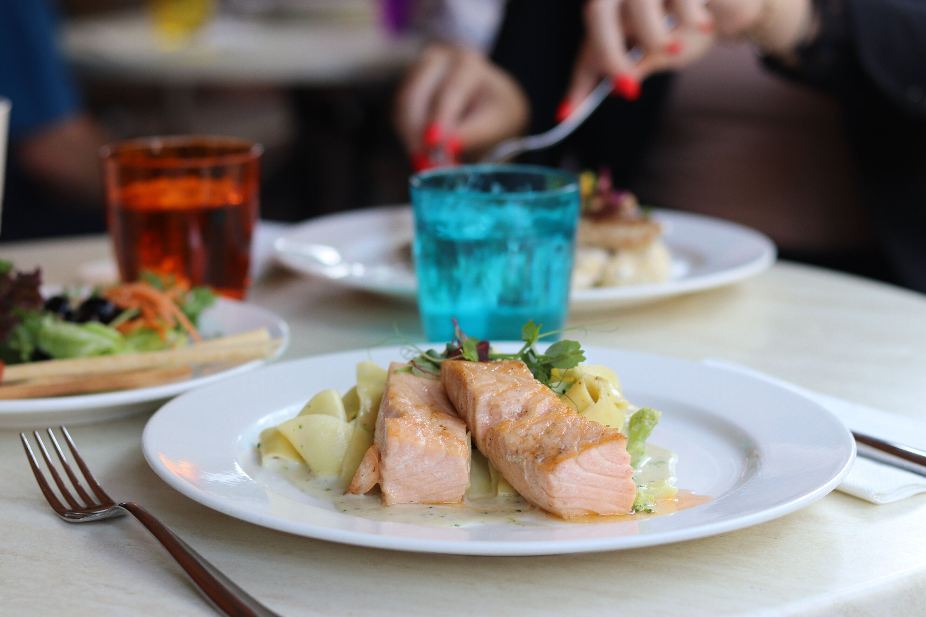 Een bord met zalm en aardappelen, een vork en een glas water op een tafel.