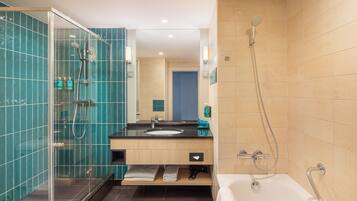 Un baño moderno con ducha envuelta en vidrio, bañera y lavamanos con espejo.
