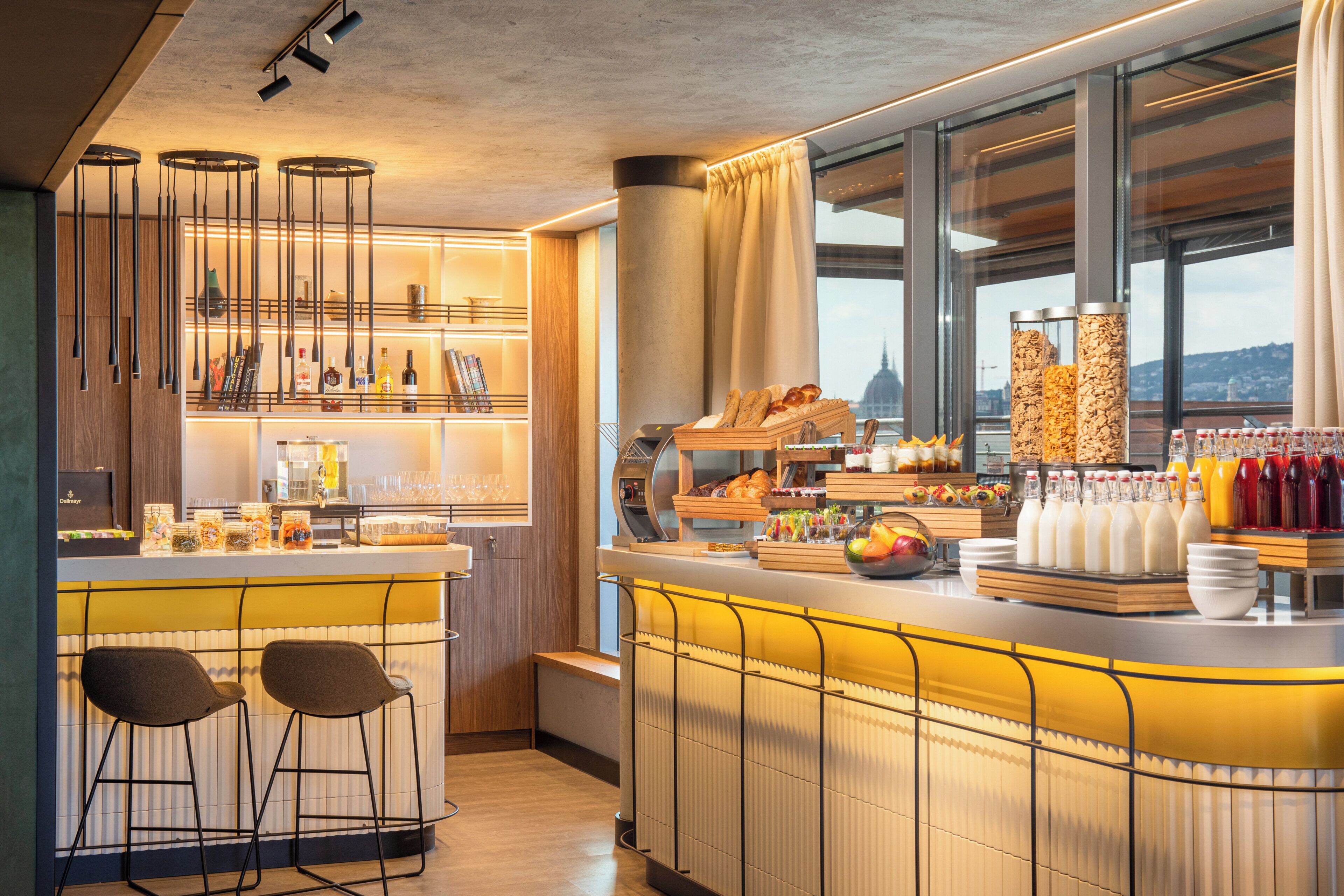 Zona moderna de bar con mostrador, taburetes y diversas opciones de comida y bebida.