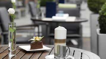 Una mesa con un pastel, una taza de café y un florero con flores.