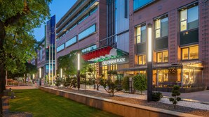 A modern building with "CROWNE PLAZA" signage, featuring multiple floors, large windows, and a well-maintained outdoor area with trees and a pathway. - Crowne Plaza Budapest by IHG (Budapest)