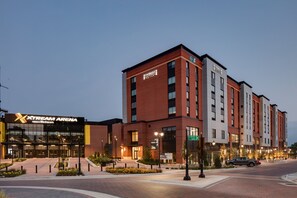 A multi-story hotel with a prominent 'XStream Arena' sign, a brick facade, and a well-lit entrance area.