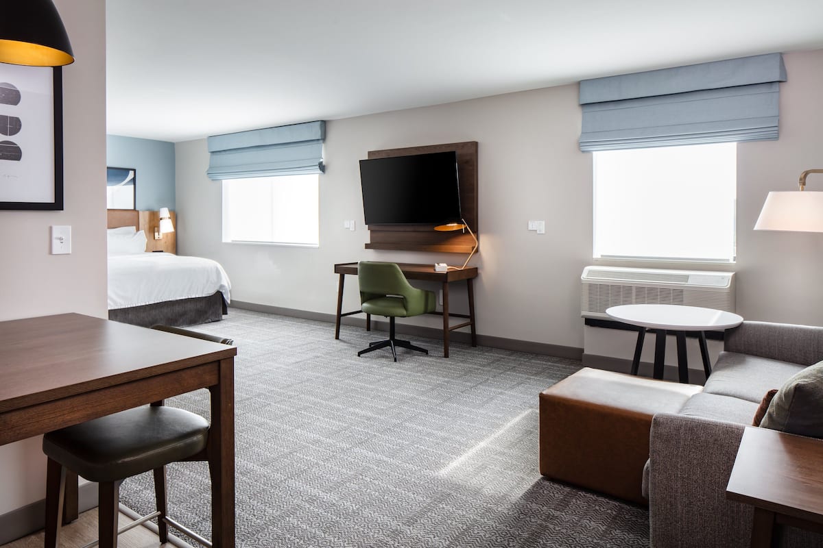 Une chambre d’hôtel équipée d’un lit, d’un bureau, d’une chaise, d’une télévision et d’un coin salon.