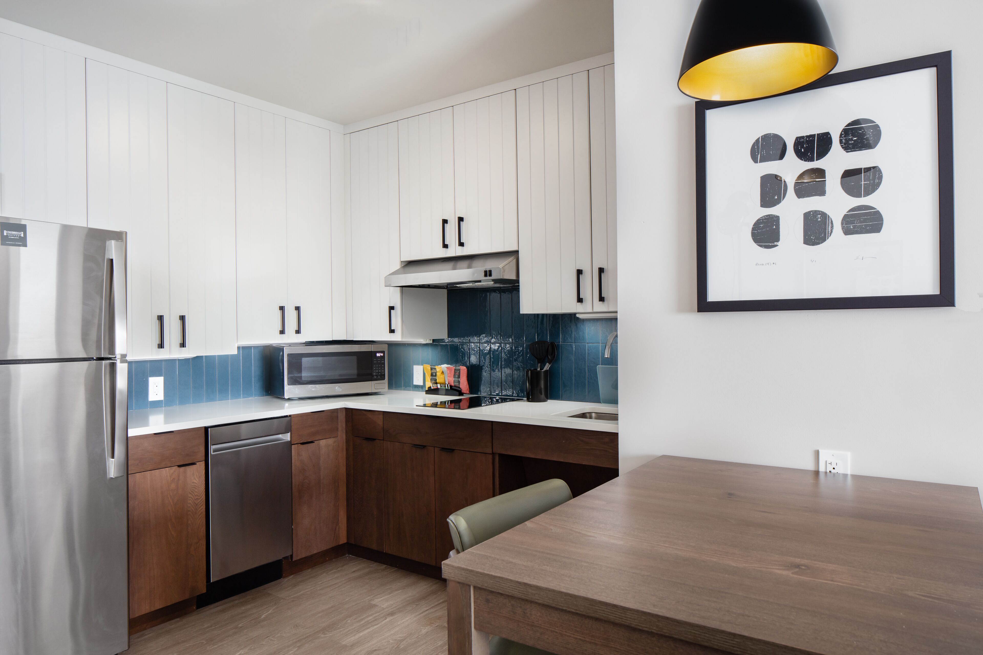 Una cucina moderna con elettrodomestici in acciaio inox, mobili in legno e un'area pranzo con tavolo in legno.