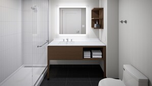 Un baño moderno con cabina de ducha de vidrio, un lavamanos blanco con mueble de madera y un inodoro.