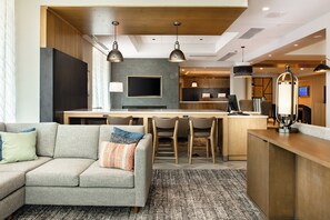 Una habitación de hotel moderna con sofá, comedor y televisión.