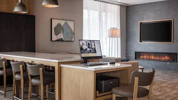 Une chambre d’hôtel moderne équipée d’un bureau, de chaises, d’un lit, d’une cheminée et ornée d’œuvres d’art sur les murs.