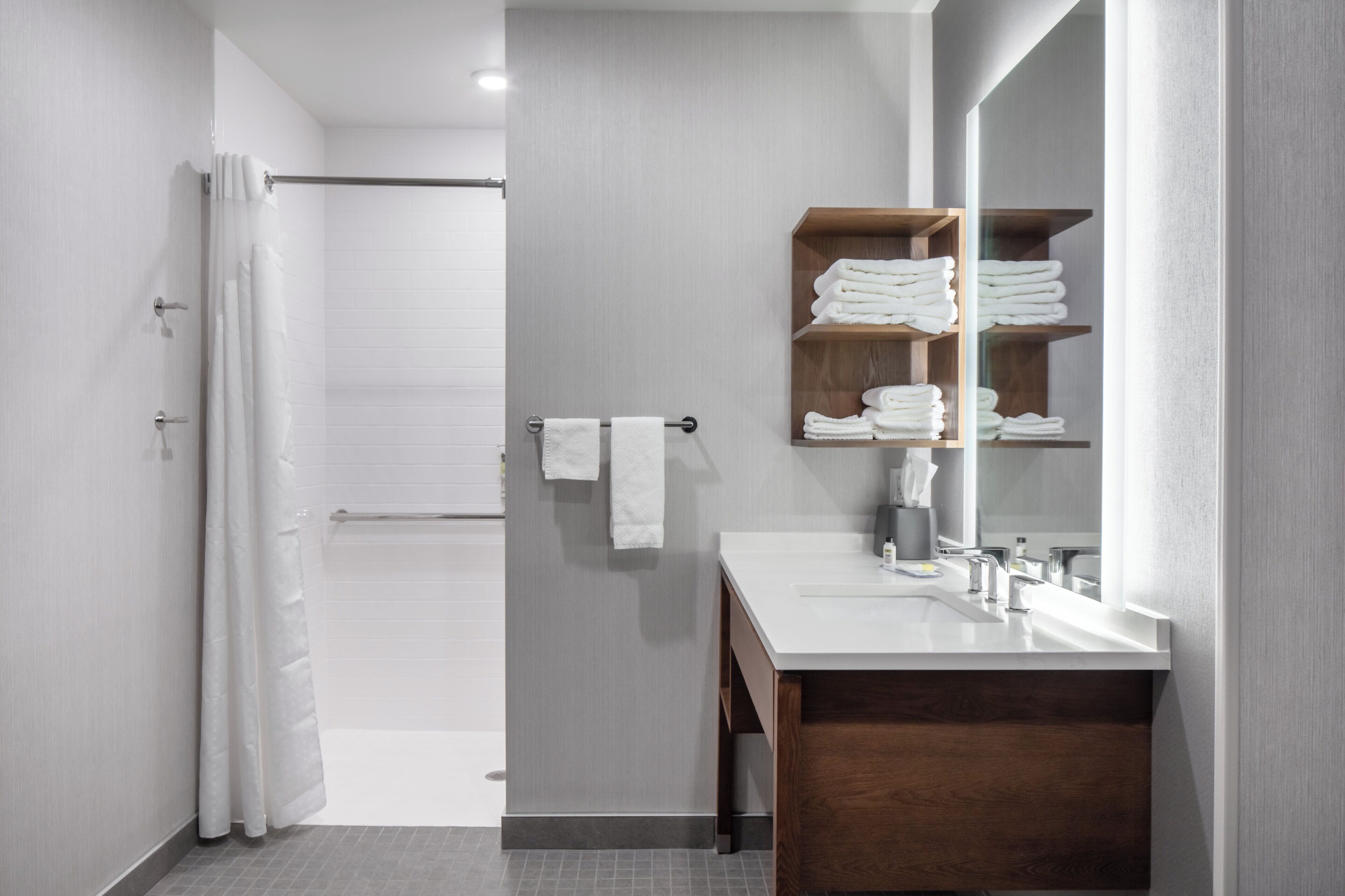 A modern bathroom with a shower, a vanity with a mirror, and a towel rack.