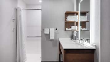 A modern bathroom with a shower, a vanity with a mirror, and a towel rack.