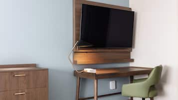 Ett modernt rum med ett skrivbord i trä, en grön stol och en väggmonterad platt-TV.