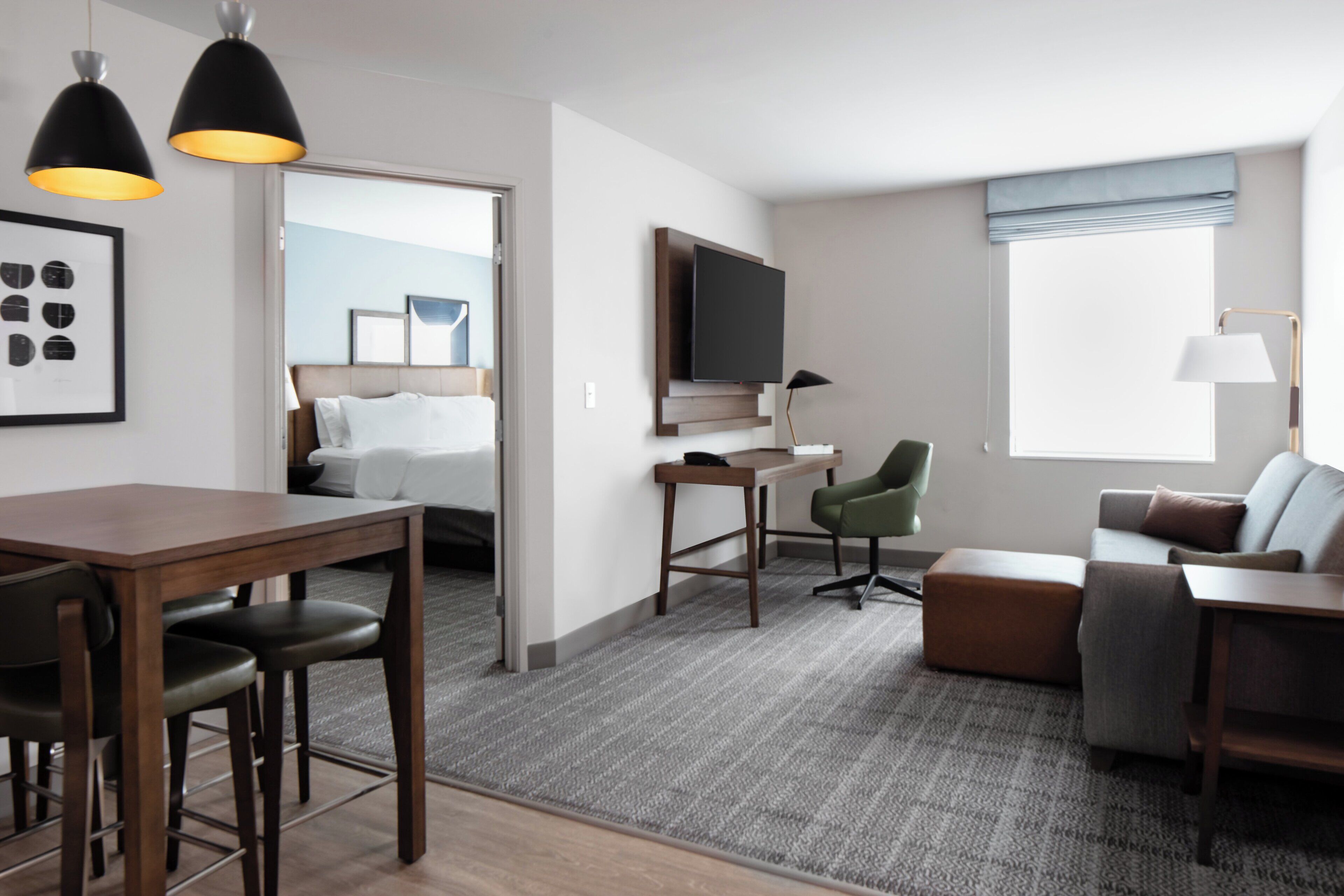 Habitación de hotel con cama, escritorio, silla, sofá y televisor.