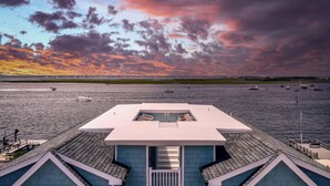 A modern building with a flat roof overlooking a body of water. - Expansive Bayfront Home w/ Heated Saltwater Pool & Dock (Ship Bottom)