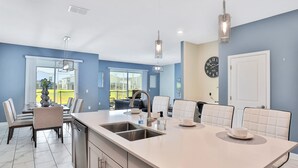 Una cocina moderna con una isla grande, pileta de acero inoxidable e iluminación colgante.