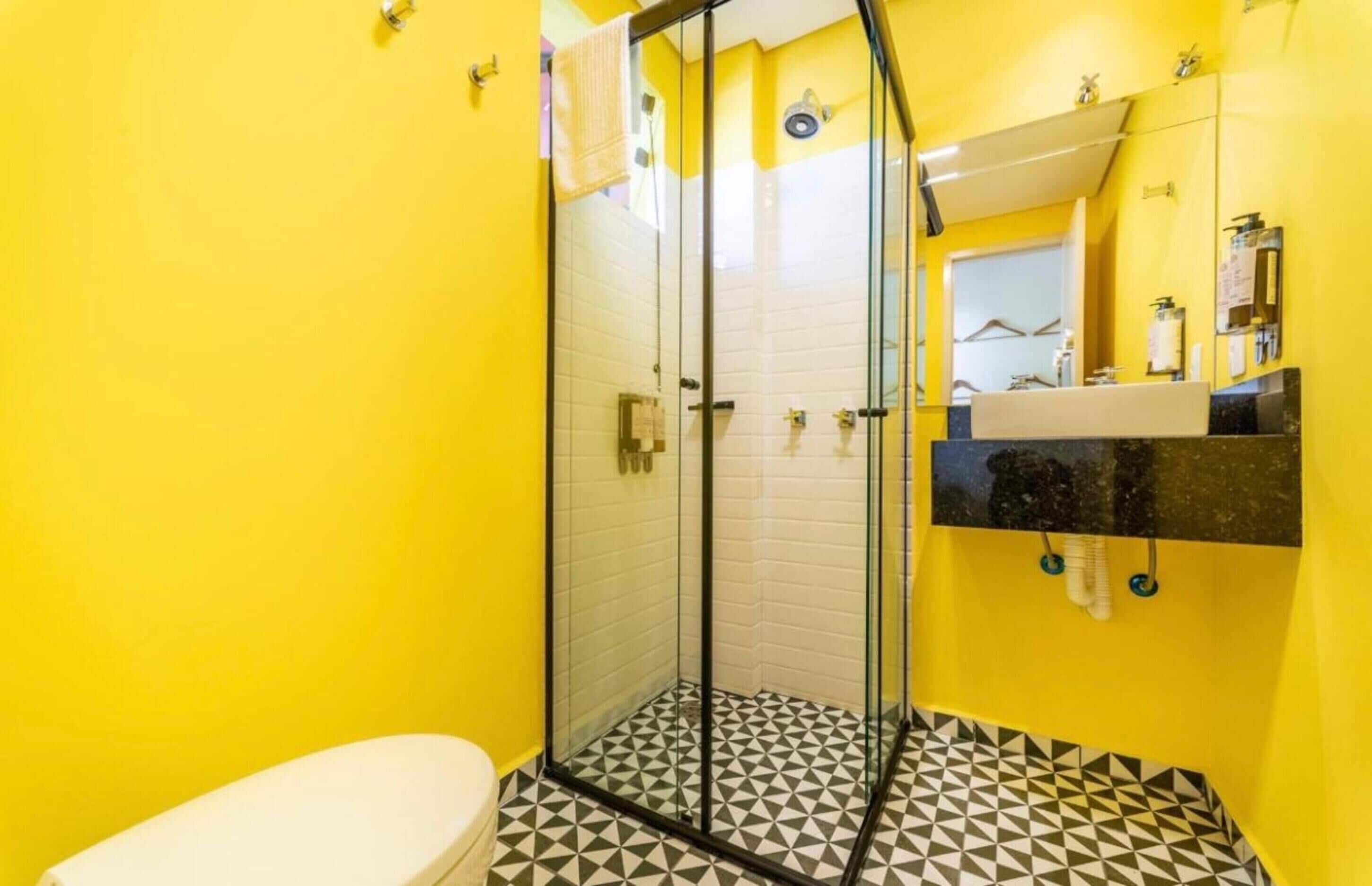 A bathroom with a glass-enclosed shower, a white toilet, and a black and white patterned floor.