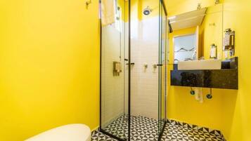 A bathroom with a glass-enclosed shower, a white toilet, and a black and white patterned floor.