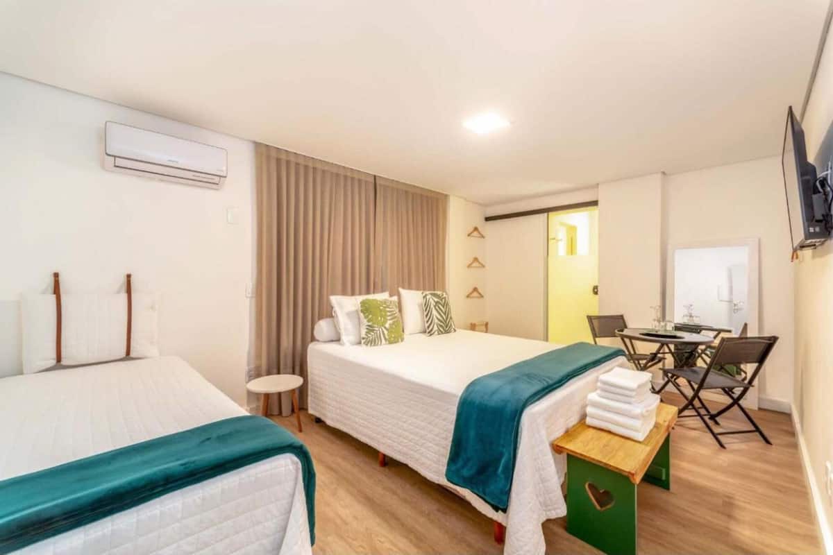 A hotel room with two beds, a desk, and a television.