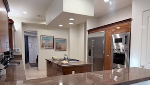 A modern kitchen with granite countertops, stainless steel appliances, and wooden cabinetry.