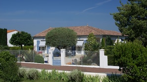 A two-story house with a tiled roof, surrounded by a fence and greenery. - Gîte Villa l'Olivier - charm, tranquility, beach at VAUX SUR MER / ROYAN. (VAUX SUR MER)