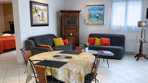 A living room with a dining table, two sofas, and a cabinet. - Gîte Villa l'Olivier - charm, tranquility, beach at VAUX SUR MER / ROYAN. (VAUX SUR MER)