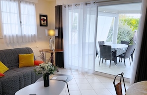 Una sala de estar moderna con sofá, mesa de centro y una zona de comedor con sillas y mesa.