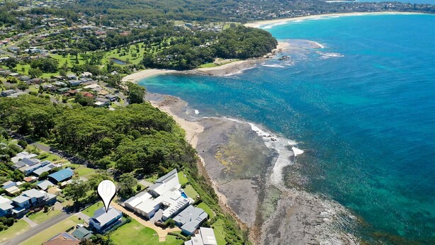 An aerial view of a coastal area with residential buildings, a beach, and clear blue waters. - Hamptons Ocean Escape - The most beautiful home for your next luxurious, relaxing getaway (Ulladulla)