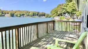 A wooden deck with a view of a lake, surrounded by houses and trees.
