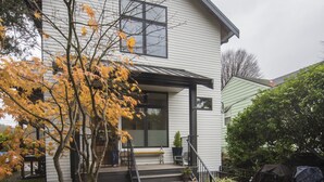 A two-story house with a front porch, a staircase leading to the entrance, and a covered outdoor seating area. - Restful, Convenient Getaway Near Downtown and Seattle’s Largest Park (Seattle)