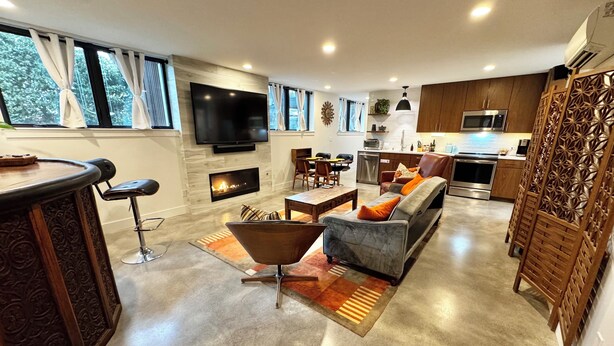 A modern living room with a fireplace, a television, and a dining area. - Restful, Convenient Getaway Near Downtown and Seattle’s Largest Park (Seattle)