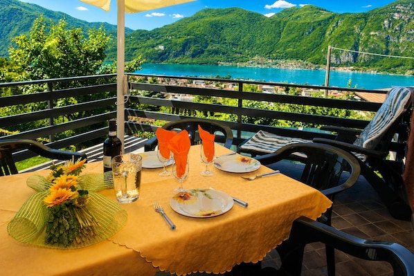 A table set with a yellow tablecloth, wine bottle, glasses, and a flower arrangement.