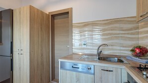 Una cocina compacta con armarios de madera, lavavajillas integrado y pileta de acero inoxidable.