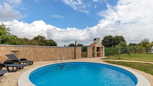 A swimming pool with a stone wall, lounge chairs, and a small building with a red roof. - Pool & Spa House Betiga 2 (Vodnjan)