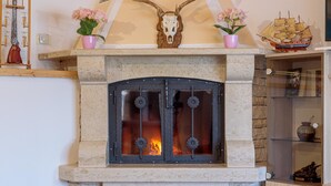 Una chimenea con repisa de piedra, cráneo de venado y un modelo de barco.